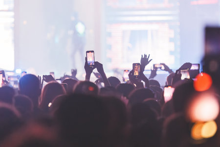 People taking pictures and recording at the big concert. Close-up shot. Streaming at the concert. High quality photoの写真素材