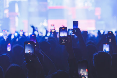 People taking pictures and recording at the big concert. Close-up shot. Streaming at the concert. High quality photoの写真素材
