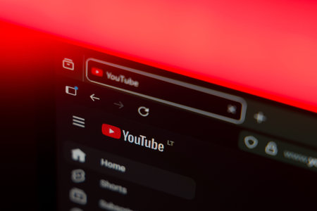 Close up of a web browser displaying the YouTube logo and home menu on a dark interface with a vibrant red lighting effect, representing online video streaming, content creation, and digital media.のeditorial素材