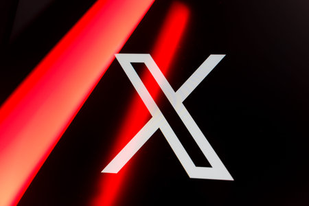 Close up of the X social media logo formerly known as Twitter on a black screen with vibrant red light streaks, representing modern digital communication, networking, and microblogging.のeditorial素材