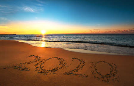 Number 2020 written on seashore sand at sunrise. Concept of upcoming new year and passing of time.の写真素材