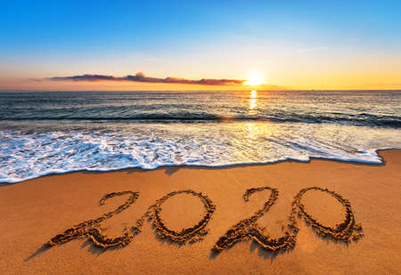 Number 2020 written on seashore sand at sunrise. Concept of upcoming new year and passing of time.の写真素材