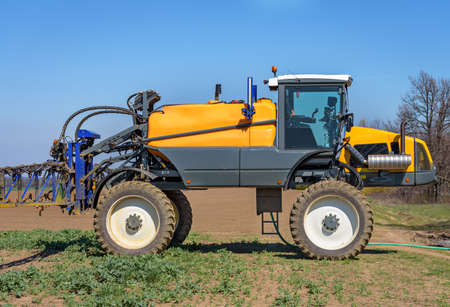 Farm machinery spraying insecticide to the green field.