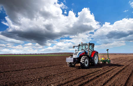 Farmer seeding, sowing crops at field. Tractor!の写真素材
