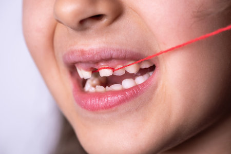 Little girl pulling her loose tooth.の写真素材