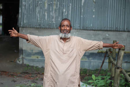 Bangladesh, Rangpur- July 03, 2021. An old man is standing with his arms outstretchedのeditorial素材