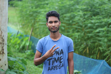 Bangladesh, Rangpur- July 03, 2021. A boys are standing with two fingers out of one handのeditorial素材