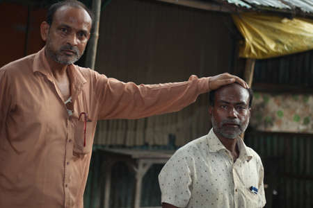Bangladesh, Rangpur- July 03, 2021. A people standing and other people put on his hand on the head.のeditorial素材