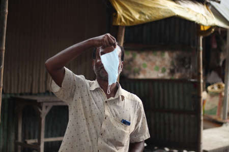 Bangladesh, Rangpur- July 03, 2021. A person standing with his mask hanging on the handのeditorial素材