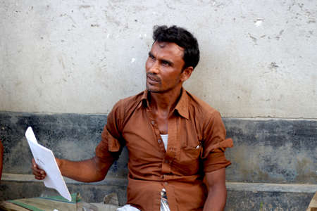 Bangladesh, Rangpur- July 12, 2021. A shopkeeper is sitting with a notebook in his hand. his behind background blur.のeditorial素材