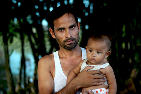 Bangladesh, Rangpur- July 12, 2021. A young man standing on the street with his baby. his behind background blur.のeditorial素材