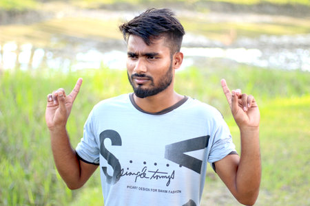 Bangladesh, Rangpur- July 12, 2021. A young man two hands up side and show his finger. his behind background blurのeditorial素材