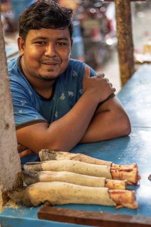 Bangladesh, Rangpur- August 31, 2021. A young boy is sitting in the open market with a cow's foot. the background blurのeditorial素材