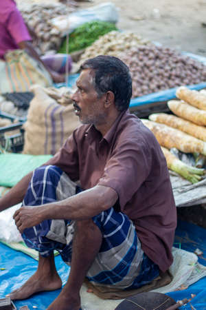 Bangladesh, Rangpur- August 31, 2021. A poor man is sitting in a makeshift shop in the market and is...