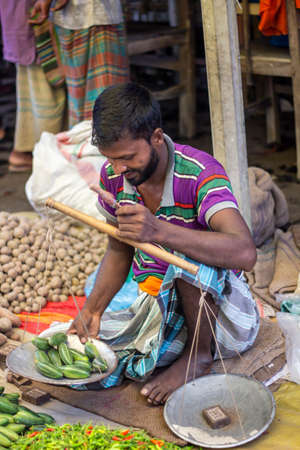 Bangladesh, Rangpur- August 31, 2021. A poor man is sitting in a makeshift shop in the market and is selling different kinds of vegetables there. the background blurのeditorial素材
