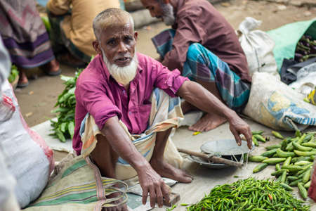 Bangladesh, Rangpur- August 31, 2021. A poor old man is sitting in a makeshift shop in the market...
