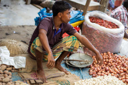 Bangladesh, Rangpur- August 31, 2021. A poor man is sitting in a makeshift shop in the market and is...