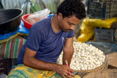 Bangladesh, Rangpur- August 31, 2021. A poor man is sitting in a makeshift shop in the market and is selling different kinds of vegetables there. the background blurのeditorial素材