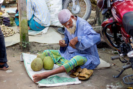 Bangladesh, Rangpur- August 31, 2021. A poor old man is sitting in a makeshift shop in the market and is selling different kinds of vegetables there. the background blurのeditorial素材
