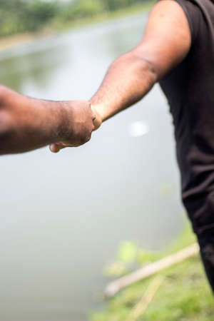 The hands of two people are shaking hands together and blurring the background behind itの写真素材