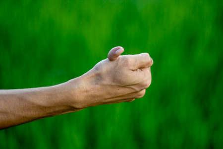 A man is showing a small finger by clenching his hand and blurring the background behind itの写真素材