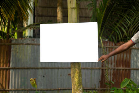 A blank white sign board hanging with a long pole on the side of the road and the background blurの写真素材