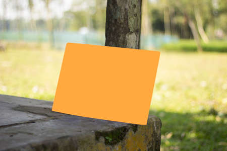 A blank yellow sign board leaning against the old walls with a pole and the background blurred.の写真素材