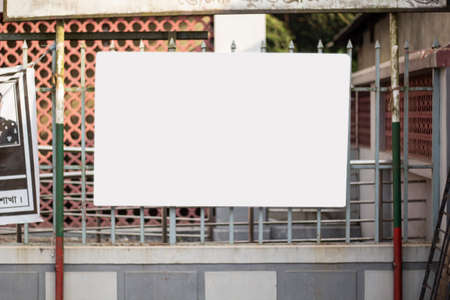 The steel grille has a large white signboard in front of it and the background behind it is slightly blurred.の写真素材