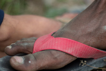 there is a man leg on the red color sandle and the background is blurredの写真素材