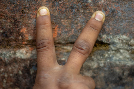 a man is show his own hand two finger and the background is blurredの写真素材