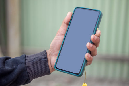 A man is holding a mobile phone in his hand and the mobile screen mockup is a black colorの写真素材