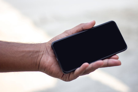 A man is holding a mobile phone in his hand and the mobile screen mockup is a black colorの写真素材