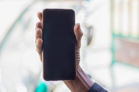 A man is holding a mobile phone in his hand and the mobile screen mockup is a black colorの写真素材