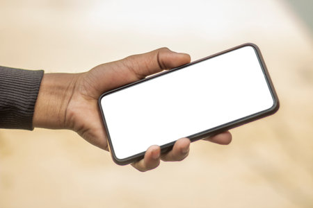 A man is holding a mobile phone in his hand and the mobile screen mockup is a white colorの写真素材