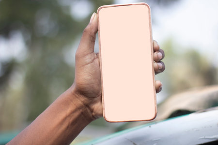 A man is holding a mobile phone in his hand and the mobile screen mockup is a white color