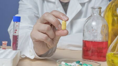 female scientist holding a yellow pill in lab.の写真素材