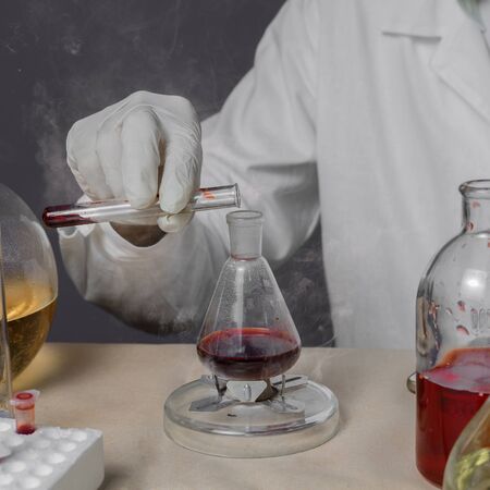 Male medical or scientific laboratory researcher performs tests with red liquid. Close upの写真素材