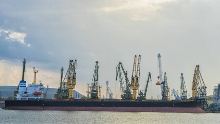 Sunset over sea port and industrial cranesの写真素材