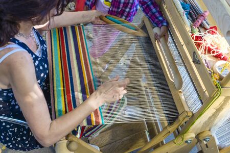 Close-up: weaving on a loom, cotton on a hand-loom in European traditional culture and a womans lifestyle, weaved by handの写真素材