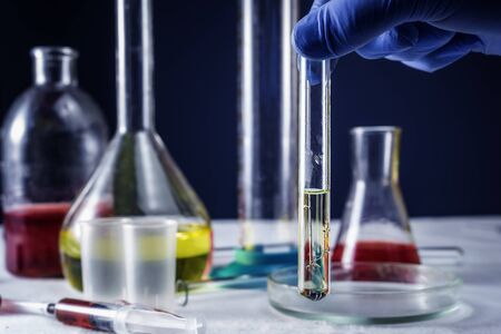 Close-up of glass tube with blue fluid in scientist hand during medical test.の写真素材