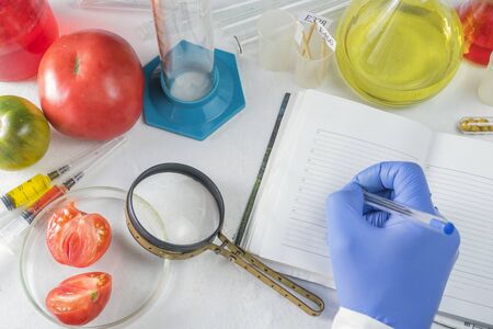 Close up of male scientist hands writing in notebook. GMO tests in the laboratoryの写真素材