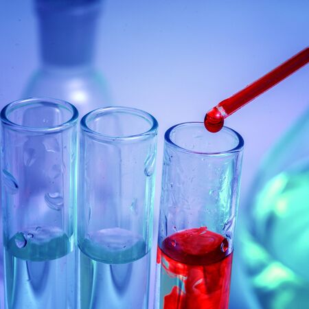 Pipette tip with a droplet blood over a rack of Eppendorf test tubes. Close up. Blue toningの写真素材