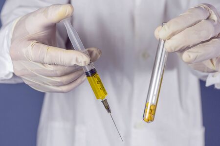 The researcher holds a test tube with soybeans and a syringe. GMO concept. Selective focus.の写真素材