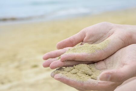 Close up sand in hand. Sand in female hand at beachの写真素材