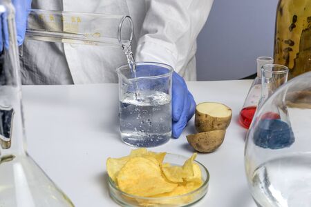 Food safety expert holding test tubes in hands checking potato chips in the laboratory.の写真素材