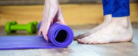 Photo Meditation session, fitness healthy mindful lifestyle concept. Hands of fit woman rolling fitness, pilates, yoga mat before or after working out in yoga studio club or at home on floor. Close up viewの写真素材