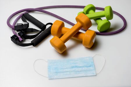 Colored dumbbells, mask. The concept of sports at home during quarantine.の写真素材