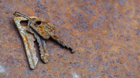 3 old rusty keys on ring shot on steel textured background. Copy space.