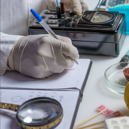 Photo Laboratory assistant at the workplace makes notes in a notebook. Laboratory procedure for food...