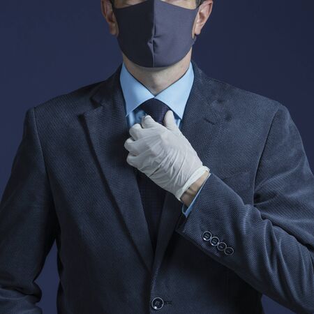 Photo businessman in medical mask and medical gloves isolated on background. Business crisis during a pandemic.の写真素材